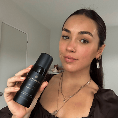 Lady holding Earthwoven soap-free cleanser, designed to soothe and cleanse acne-prone skin gently.